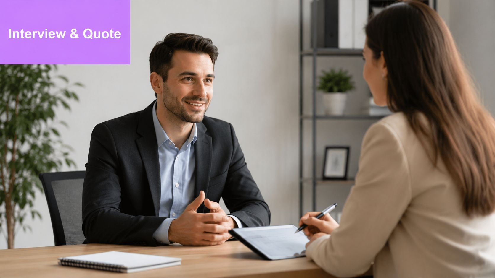 A professional man and woman having a business interview at a wooden desk in an office.
