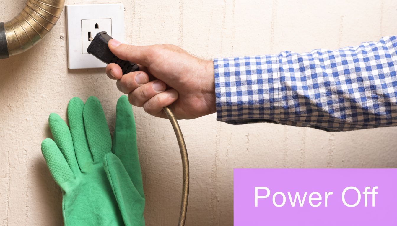 A person in a checkered shirt unplugging a kitchen appliance while wearing a green cleaning glove.